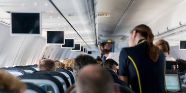 Darf ich betrunken fliegen? Flugzeugkabine mit Passagieren und Stewardess