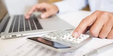 Taschenrechner Hände, die auf einem Taschenrechner und einer Tastatur tippen